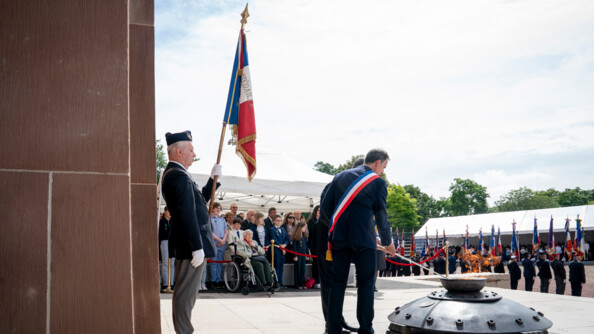 Plan large montrant le président de la République en train de raviver la flamme.