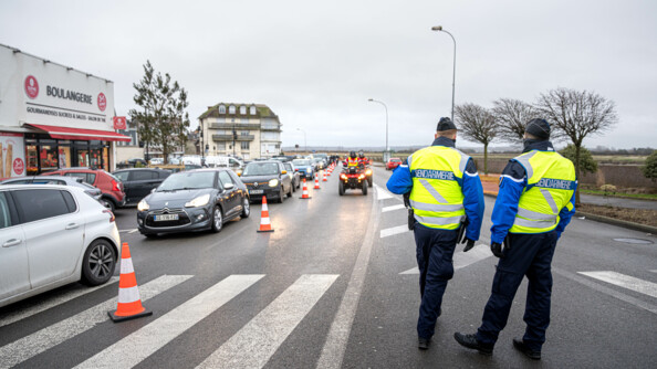 Photo de deux réservistes de dos gérant la gestion du flux. Sur la gauche on peut voir une file de voiture ainsi que deux quads de sapeurs pompiers arriver.