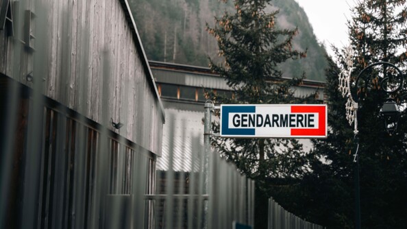 Façade d'une brigade de gendarmerie de montagne. On aperçoit la pancarte "gendarmerie" de couleur bleu, blanc et rouge, et la montagne se dressant en arrière plan.