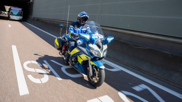 un gendarme motocycliste roule sur la route. Au sol est inscrite l'inscription Paris 2024.