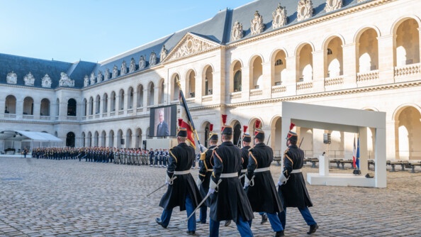 Dans la cour des invalides, des gendarmes de la Garde marchent.