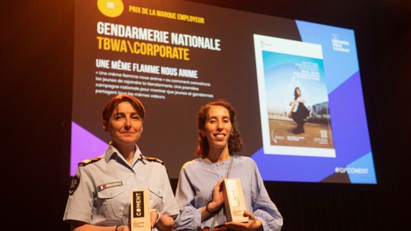 Sur l'image, la commandante Raboin, cheffe de la section des études et de la communication du Bureau du Recrutement, des Concours et des Examens, tient dans ses mains le premier prix qui vient d'être remis à la gendarmerie. Derrière elle, un écran met en avant la campagne de recrutement.
