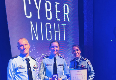 Trois gendarmes (deux hommes et une femmes) posent fièrement, un prix à la main, deavtn un kakémono portant la mention Edition 2024 - CYBERNIGHT