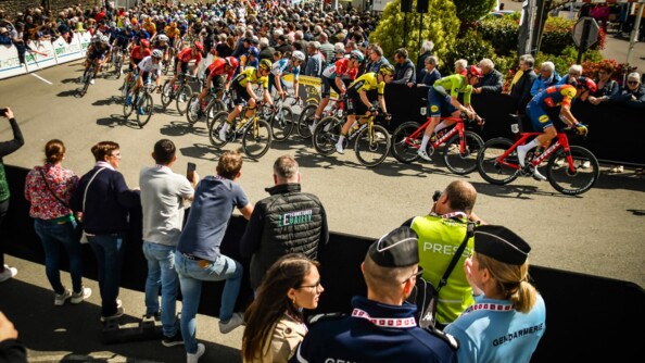 Passage de la course cycliste devant deux gendarmes de dos au premier plan