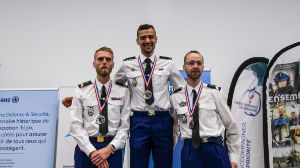3 gendarmes en tenue chemise blanche sur le podium avec Medhi Frère au milieu, qui tient les deux autres par les épaules