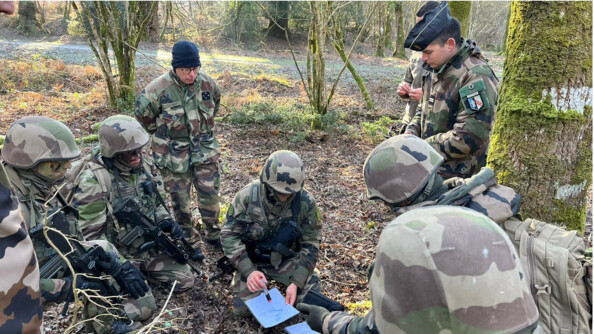 9 gendarmes entrain de faire un briefing. Parmi les 9, 5 sont accroupis. Un gendarme au centre tiens des feuilles et parle aux autres. Derri&egrave;re lui, debout, se trouve le G&eacute;n&eacute;ral de corps d'arm&eacute;e Andr&eacute; P&eacute;tillot, major g&eacute;n&eacute;ral de la gendarmerie nationale.