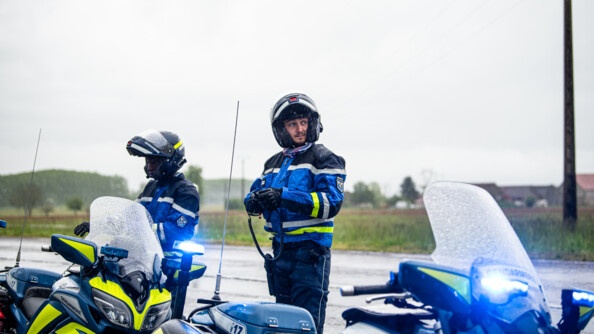 Deux officiers-élèves motards sont arrêtés sur le bas côté pour prendre en compte les informations liées à l'accident de bus
