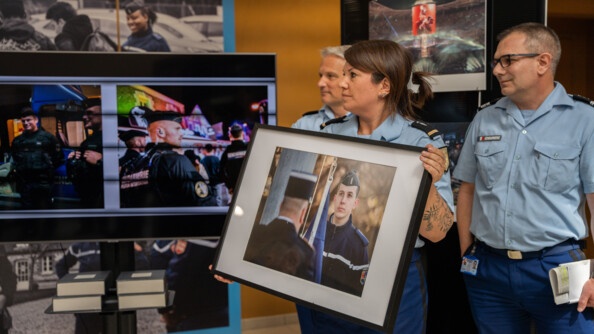 Une gendarme tient la photo qui a &eacute;t&eacute; s&eacute;lectionn&eacute;e par Vincent Montagne. La photo repr&eacute;sente une jeune gendarme qui regarde au loin, tenant sur son &eacute;paule droite le drapeau fran&ccedil;ais lors d'une c&eacute;r&eacute;monie des couleurs. Derri&egrave;re la gendarme, de gauche &agrave; droite, le g&eacute;n&eacute;ral Lettermann et le colonel Coulbeau.