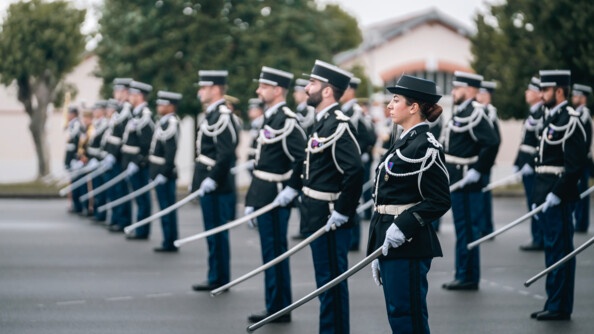 Des élèves-officiers en tenue de cérémonie levant le fourreau et au porter sabre