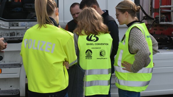 Trois femmes revêtues de chasubles jaune et deux hommes en civil contrôlant un camion