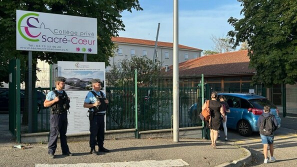 Deux gendarmes devant les grilles d'un collège.