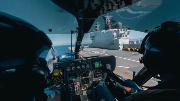 Equipage d'hélicoptère des Forces aériennes de la gendarmerie nationale, en vol, en approche du Porte hélicoptères amphibie Mistral de la Marine nationale.