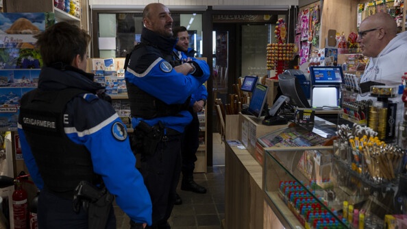 Trois gendarme dans un bureau de tabac donc celui du milieu, plus grand, les bras croisés et souriant