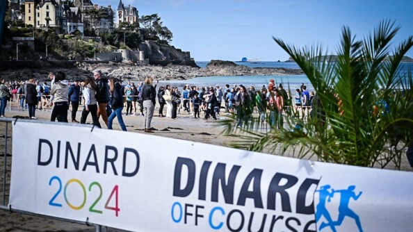 Banderole Dinard Off Course devant la plage de Dinard et la mer, avec de très nombreuses personnes sur la plage.
