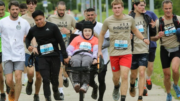 Une douzaine de coureurs dont trois courent avec une joëlette, arborant un t-shirt bege "la Frileuse", le nom du camp de Beynes