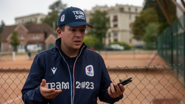 Lieutenant Aurélien Le Frapper debout, de face, en train de parler, vêtu d'une veste et d'une caquette de couleur bleu marine portant l'inscription "Team 2023"