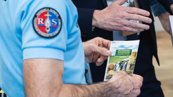 Un gendarme référent sûreté tient un dépliant sur la sécurisation des exploitations agricoles.