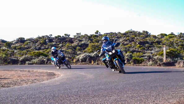 Sur la route, un motocycliste de la gendarmerie ouvre la voie. Derrière lui, un motard, civil le suit.
