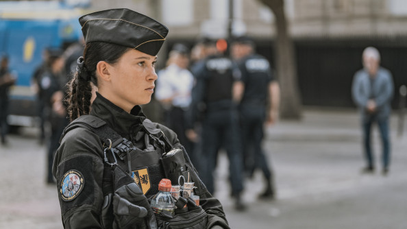 Photo d'une jeune femme gendarme, debout, de biais, dans la rue