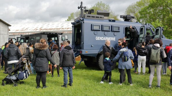 Des familles au pied d'un Centaure et d'un blindé police