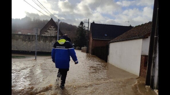 Un gendarme entrain de marcher dans une rue inond&eacute;e