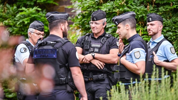 Un groupe de cinq gendarmes dont deux militaires de PSIG, en noir, échangent, encadrés par de la végétation