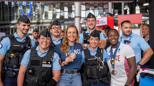 Les Sportives de haut niveau de la Défense - gendarmerie (SHND-G) Lisa Barbelin, médaillée de bronze en tir à l'arc, et Clarisse Agbégnénou, médaillée d'or et de bronze en judo, prennent la pose avec les gendarmes sur le stand du ministère de l'Intérieur et des Outre-mer, au Club France du Parc de La Villette.