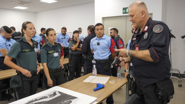 Un cadre italien montre comment fonctionne le pistole Beretta à des stagiaires. Sur la table est posé un blue gun, un chargeur et une cible.