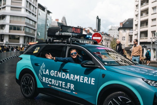 Un gendarme dans un véhicule de la caravane du Tour de France féminin salue le public.