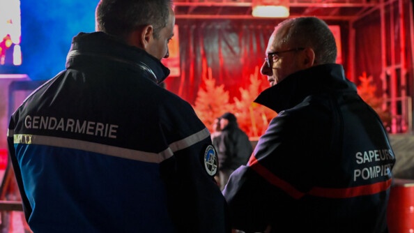 De nuit et en extérieur, un gendarme ( à gauche de l'image) échange avec un sapeur pompiers (à droite) également engagé sur la sécurisation de la course.