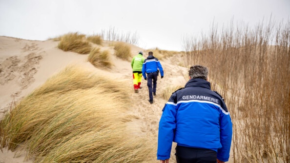 Photo de deux membres du CESAN et d'un membre de la société privée de sécurité GAEA. Ils montent les dunes, qui sont protégées et fermées au grand public.