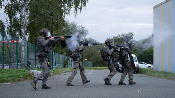 Une colonne d'assaut de quatre &eacute;quipiers de la force intervention du GIGN progresse, fusil en joue, en direction d'un hangar.