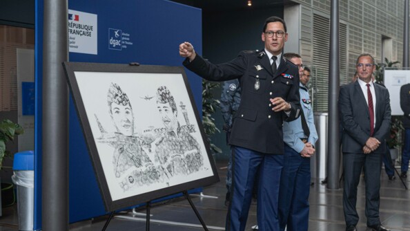 Le colonel Phlippe Mirabaud, commandant la gendarmerie des transports aériens, est à côté d'un tableau des70 ans de la GTA. Il le présente à l'assemblée présente lors de son inauguration.