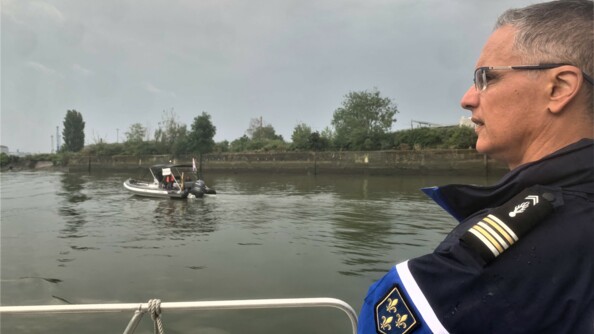 Un gendarme regarde un semi-rigide de la presse passer.