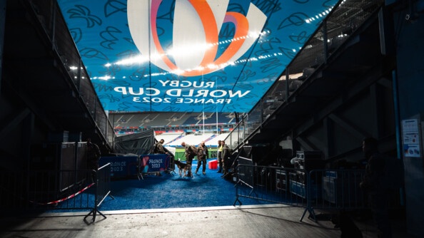 Une équipe cynophile inspecte l'entrée de la pelouse du Stade de France sous une bâche de la Coupe du Monde de rugby.