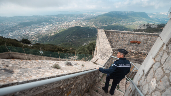 Dans un fort sur les hauteurs de Toulon, un gendarme de l'armement regarde la vue composée de Toulon et de la mer.