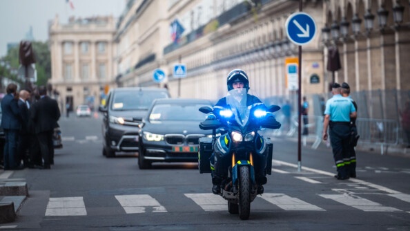 Motocycliste escortant deux véhicules au centre de Paris.