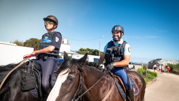 Un gendarme et une policière municipale surveillent une plage à cheval.