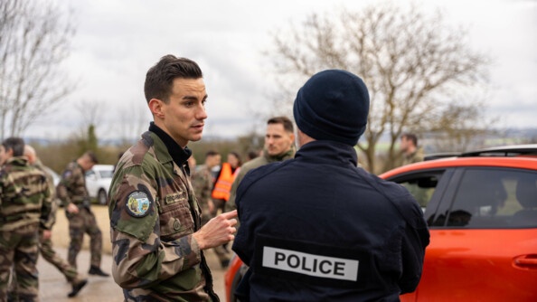 Un gendarme runner, à gauche de face, échange avec un policier (de dos)