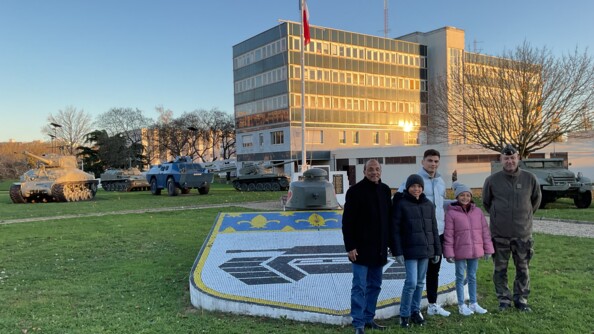 Les enfants se tenant devant l'entrée du site, véhicules blindés en arrière plan.
