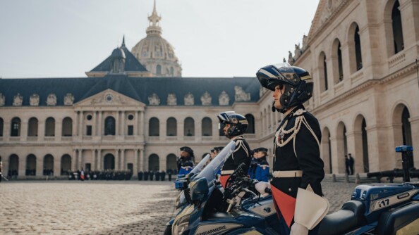 Des motards dans une cour pavée avec d'autres gendarmes, aux invalides