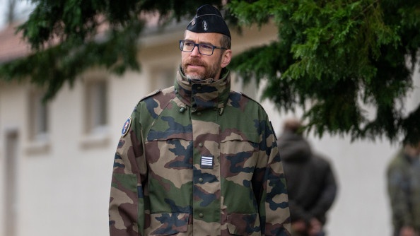 Photo d'un officier de gendarmerie, en tenue kaki, marchant en ext&eacute;rieur. Ag&eacute; d'une quarantaine d'ann&eacute;e, l'homme porte une barbe et des lunettes.