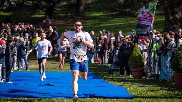 Photo d'un homme, à l'arrivée d'une course, foulant un tapis bleu