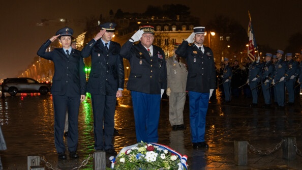 Deux policiers allemands et deux gendarmes fran&ccedil;ais dont un g&eacute;n&eacute;ral saluent militairement. A droite en arri&egrave;re-plan, des militaires. La nuit et la pluie sont sur la ville