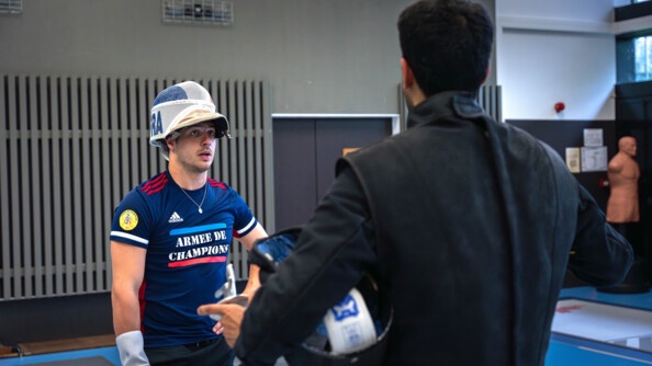 Face à son coach, casque relevé, Maxime Pauty le regarde qui s'entretient avec lui