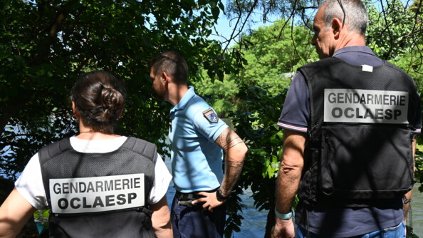 Trois gendarmes, dont deux de l'OCLAESP, de dos au bord d'une rivi&egrave;re.