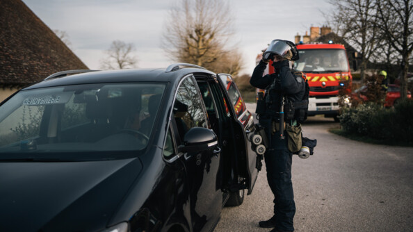 1 opérateur AGIGN s'équipe, un camion de pompiers en arrière plan