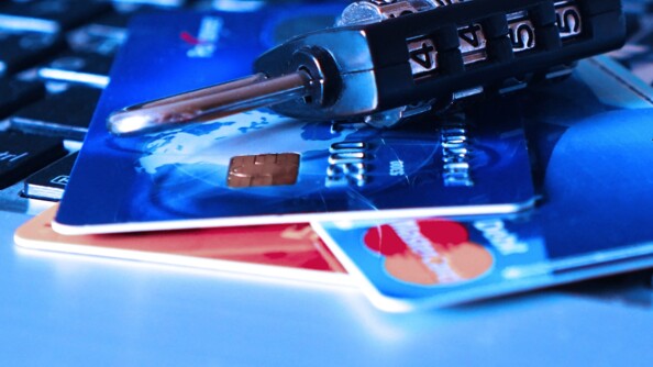 Trois cartes bancaires empilées surmontées d'un cadenas à code fermé, avec le code 4455