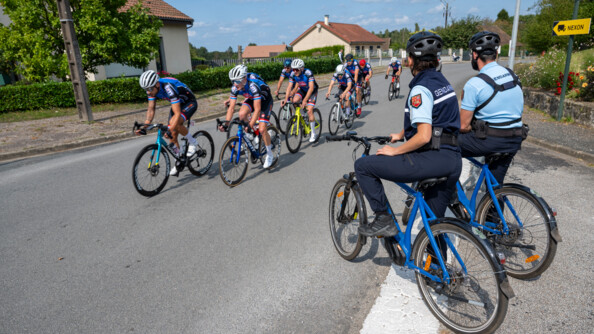 Deux gendarmes à vélo en bord de route sécurisent le 25e championnat de France de cyclisme gendarmerie.