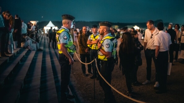 Deux gendarmes de part et d'autre d'un cordon de sécurité, de nuit, dans les jardins de Chambord